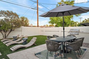 A backyard with a barbecue grill, a round table with chairs, and a lounge area with curved benches. - Scottsdale Sheridan Luxe 🌵⛳ Free Heated Pool Near Old Town & Desert Botanical (Scottsdale)