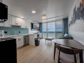 Una cocina moderna con vista al mar, un comedor con mesa y sillas, y un balcón con vistas.