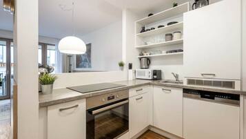 A modern kitchen with white cabinetry, a built-in oven, a microwave, and a coffee maker on the countertop.