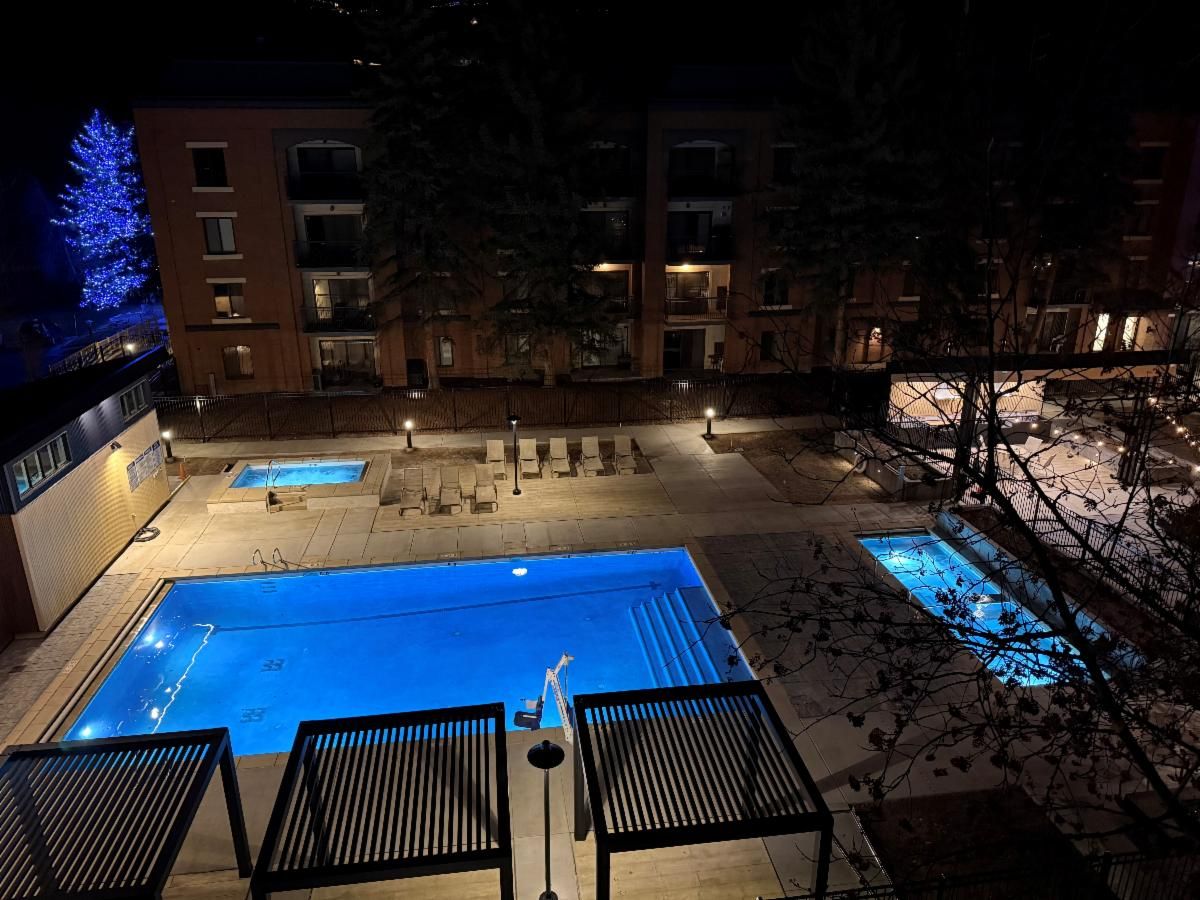An outdoor swimming pool area with lounge chairs and a building in the background.