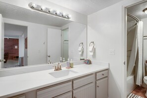 A bathroom with a white vanity, a large mirror, a shower curtain, and a visible door leading to another room. - Main Street Walk to Everything and Town Lift 146 (Park City)
