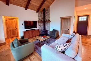 A living room with a sofa, armchairs, a television, a fireplace, and wooden flooring. - The Oar Lock Cottage (Ennis)