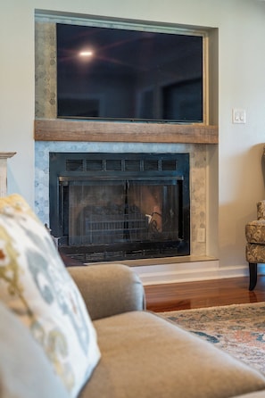 A living room with a fireplace, a sofa, and a rug. - Lake Views | Two King Suites | Pool Access (Hot Springs)