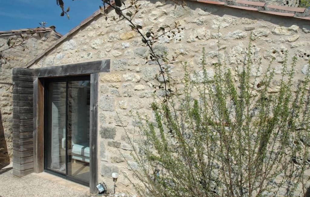 Un edificio de piedra con una entrada de vidrio moderna y un pequeño jardín.