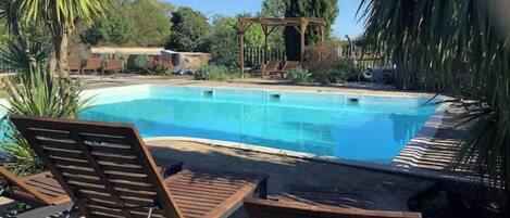 Una piscina con sillones de descanso y un pérgola.