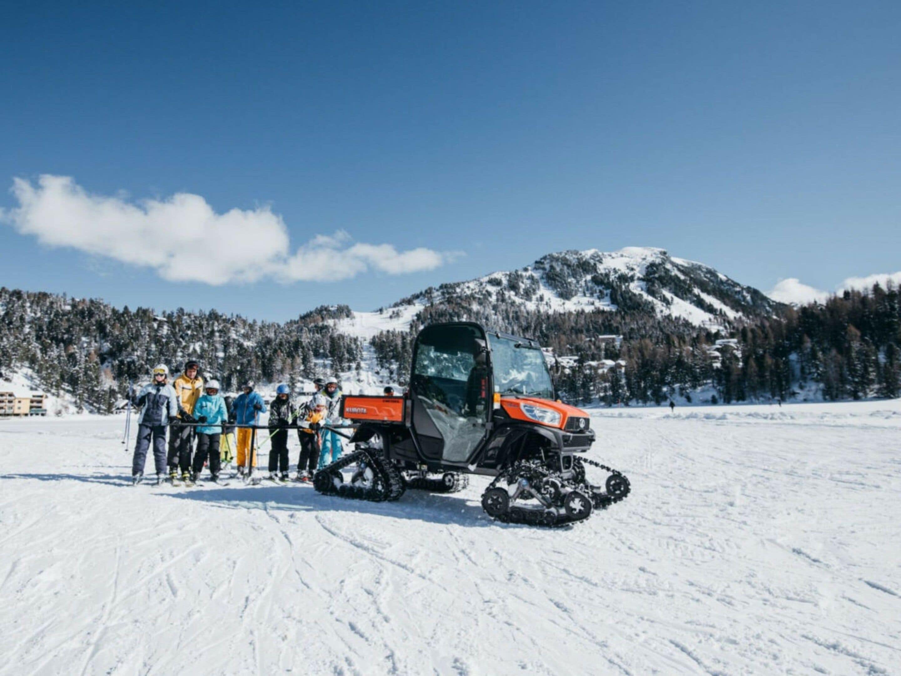 A group of people standing in a snowy field with a snowmobile in the foreground.