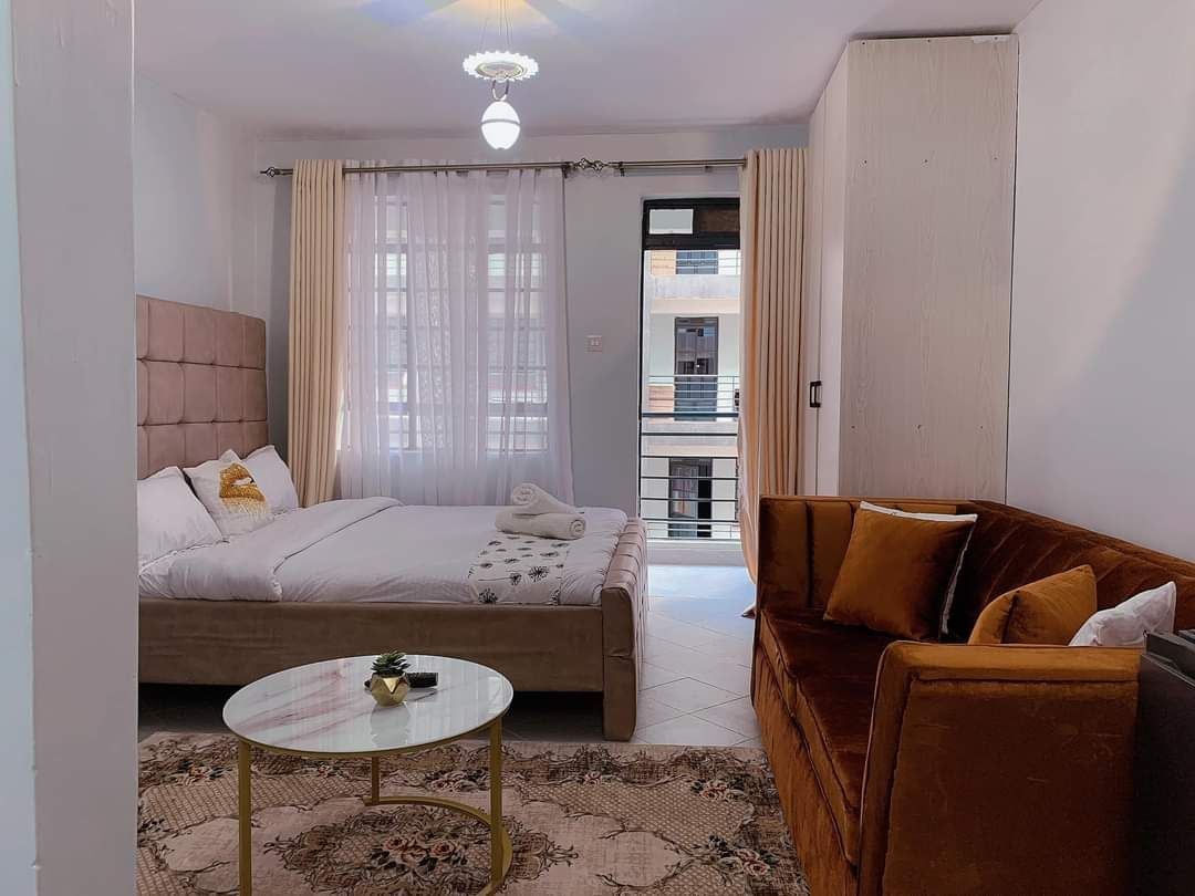 Un dormitorio con cama, una mesita de centro redonda, un sofá y vista a un balcón exterior.