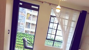 Ein Hotelzimmer mit einem Bett, einem kleinen Tisch, einem Stuhl und Blick auf einen Balkon mit Sitzgelegenheit.