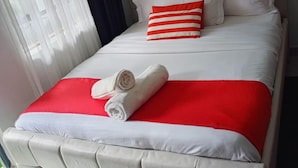 Ein Bett mit Kopfteil, Kissen und einer roten und weißen Decke.