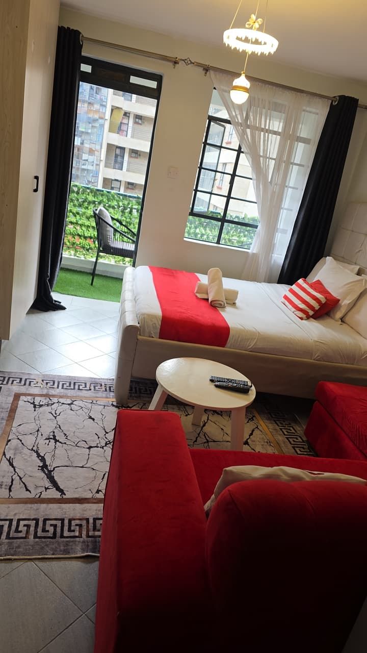Habitación de hotel con una cama, una mesita, una silla y vistas a un edificio a través de una ventana.