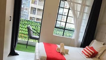 Habitación de hotel con una cama, una mesita, una silla y vistas a un edificio a través de una ventana.