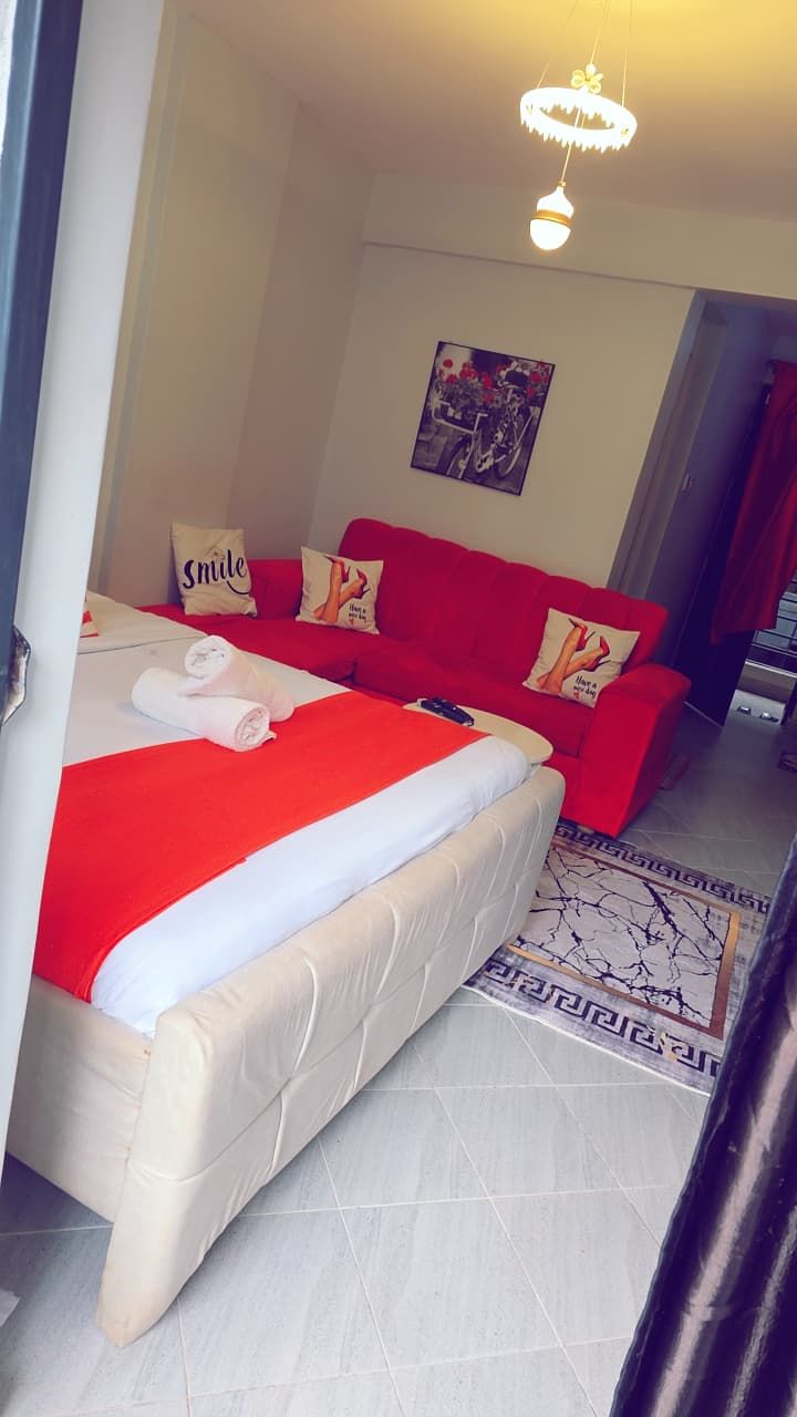 Una habitación de hotel con una cama, un sofá rojo y un cuadro en la pared.