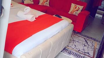 Una habitación de hotel con una cama, un sofá rojo y un cuadro en la pared.