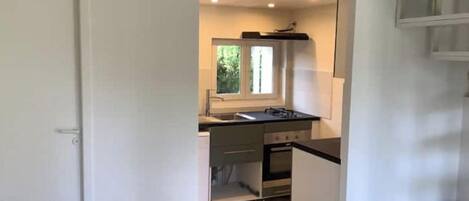Una cocina pequeña con ventana, estufa y lavabo.