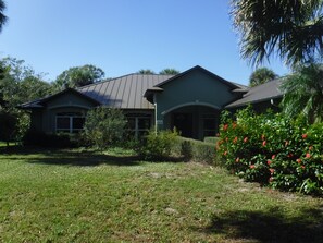 A two-story house with a green roof and a well-maintained lawn. - Peaceful home on an enchanting private pond, minutes to everything in Vero Beach (Vero Beach)