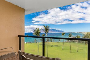 Ein Balkon mit Blick auf einen Golfplatz, das Meer und ferne Berge.