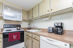 A compact kitchen with a microwave, stove, toaster, coffee maker, and dishwasher. - Oceanfront 6th Floor - Keawakapu Beach - Pool + AC (Kihei)