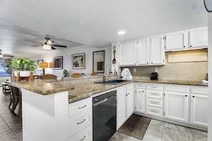 A modern kitchen with white cabinets, a granite countertop, and a dishwasher. - Kailua-Kona, Holualoa Bay Villas, Spacious 4 BR, Beachfront, Sleeps 12 (Kailua-Kona)