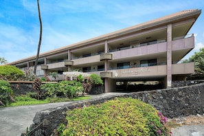 A multi-story hotel with a flat roof and balconies, surrounded by landscaped gardens and a stone wall. - Kailua-Kona, Holualoa Bay Villas, Spacious 4 BR, Beachfront, Sleeps 12 (Kailua-Kona)