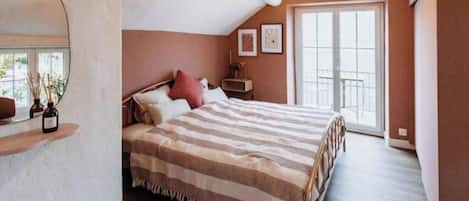 Une chambre à coucher avec un lit, une table de chevet, un miroir et une fenêtre.
