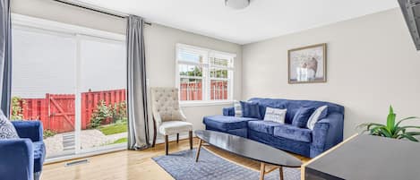 A modern living room with a blue sofa, a white armchair, and a coffee table.