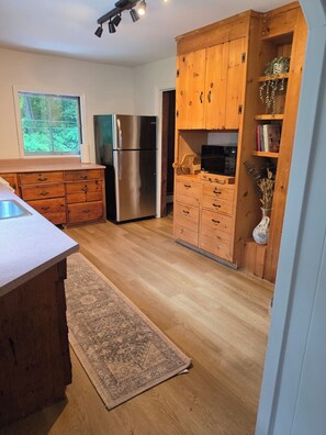 A kitchen with wooden cabinets, a stainless steel refrigerator, and a built-in oven.