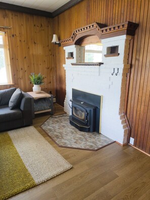 A room with a fireplace, wooden walls, a sofa, and a rug.