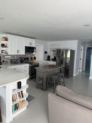 A modern kitchen with white cabinetry, stainless steel appliances, and a central island with stools. - Relax and Unwind (Saint James City)