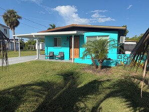A single-story house with a porch, a small palm tree, and a clear sky. - Relax and Unwind (Saint James City)