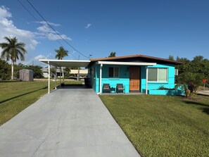 A single-story house with a covered porch, a front door, and two chairs outside. - Relax and Unwind (Saint James City)