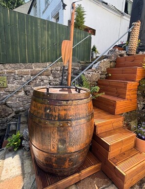 Ein Holfass mit einem Paddel, eine Holztreppe und eine Steinmauer.