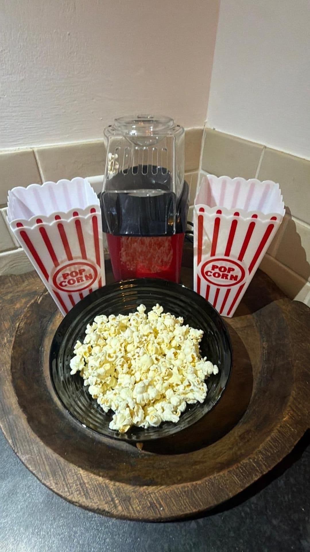 Ein Holztablett mit einer Schüssel Popcorn und zwei Popcorntüten.