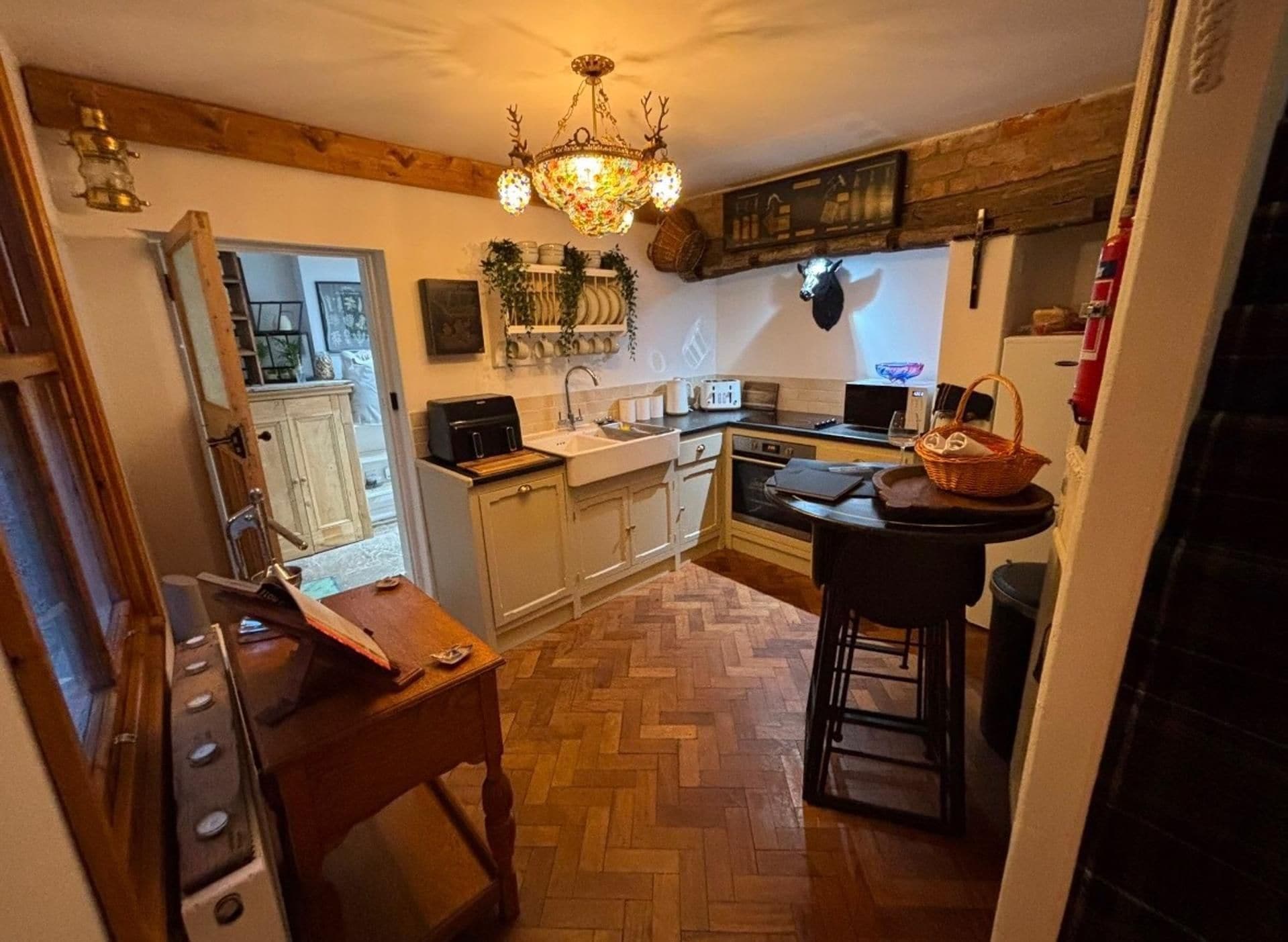 A kitchen with wooden cabinets, a herringbone floor, a chandelier, and a microwave.