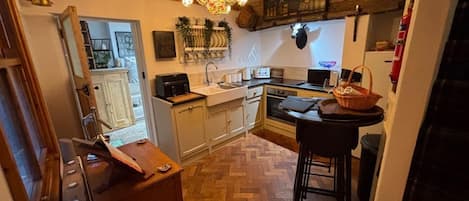 A kitchen with wooden cabinets, a herringbone floor, a chandelier, and a microwave.