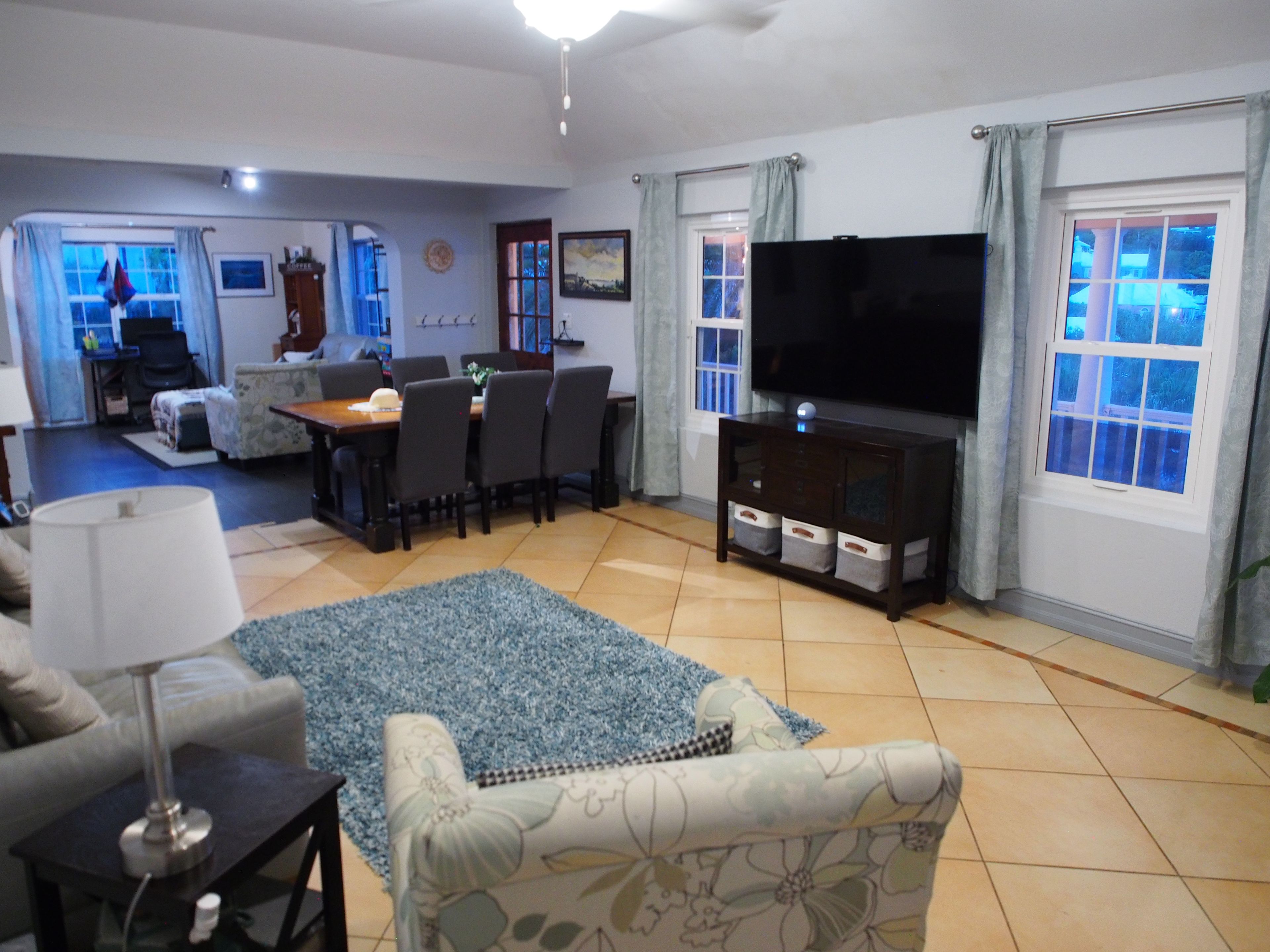 A living room with a sofa, a coffee table, a TV, and a dining area with chairs and a table.