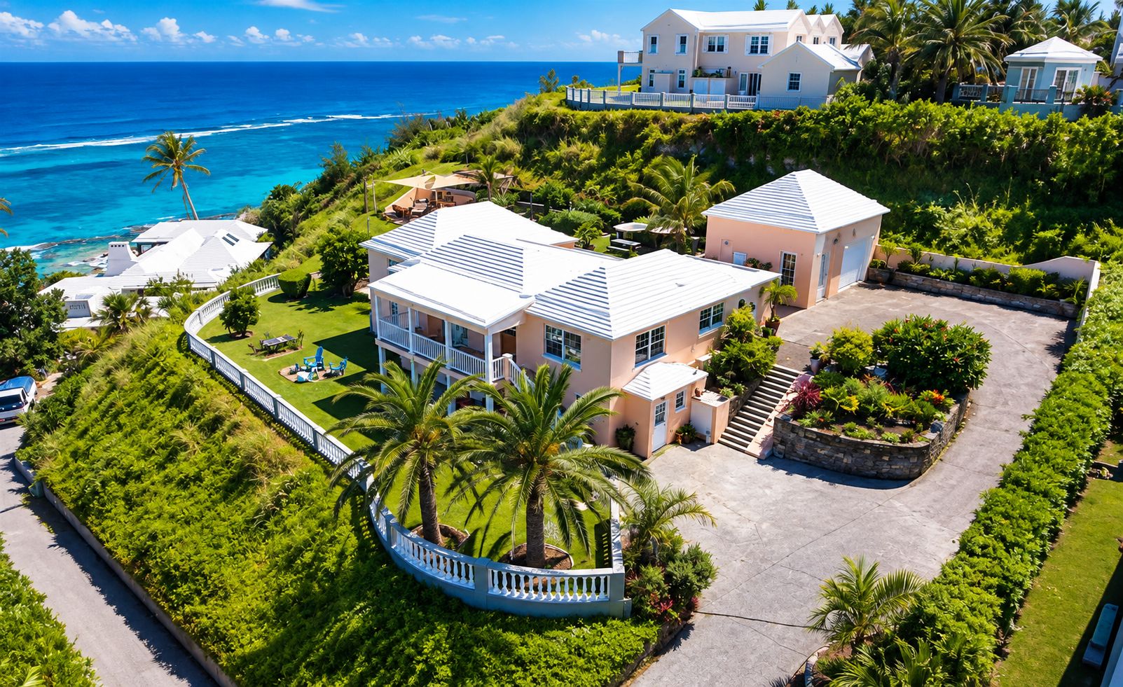 A coastal property with multiple buildings, a well-maintained lawn, and a view of the ocean.