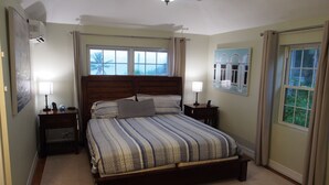 Une chambre à coucher avec un lit, des tables de chevet, un ventilateur de plafond et des fenêtres.