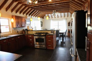 A kitchen with wooden beams, a stove, and a refrigerator.