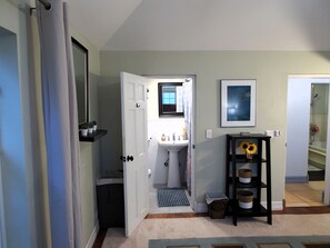 A hallway with a white door, a sink, a framed picture, and a shelf with baskets. - Spacious 3-Bedroom Bermuda Home with Spectacular Ocean Views (FL)