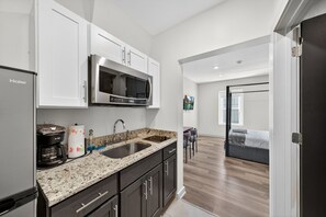 A modern kitchen with a stainless steel refrigerator, a microwave, and a coffee maker. - The Columbus Hotel - The Reimagined Suite - 52-304 (Middletown)