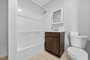 A bathroom with a bathtub, a toilet, a vanity with a mirror, and a towel rack. - The Columbus Hotel - The Reimagined Suite - 52-304 (Middletown)