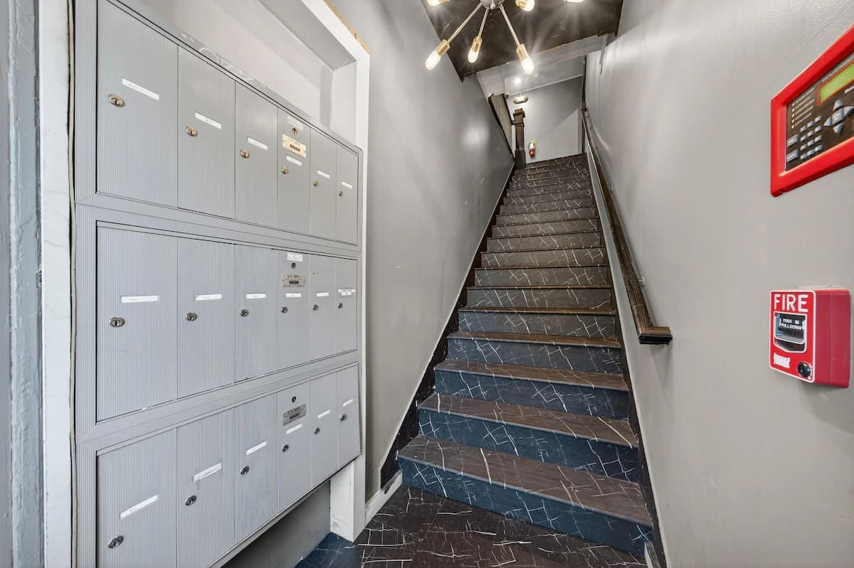 A staircase with a fire alarm and a row of lockers.