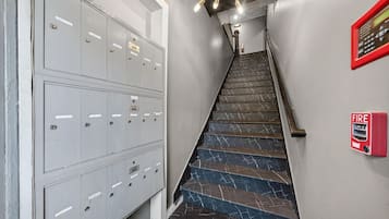 A staircase with a fire alarm and a row of lockers.