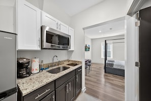 A modern kitchen with a built-in microwave, a coffee maker, and a sink. - The Columbus Hotel - The Market Suite - 52-202 (Middletown)