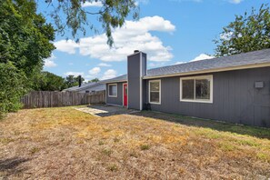 A residential property with a fenced backyard, a red door, and a chimney. - New! East Austin 4BR w/Fenced Yard, Patio + Dogs (Austin)