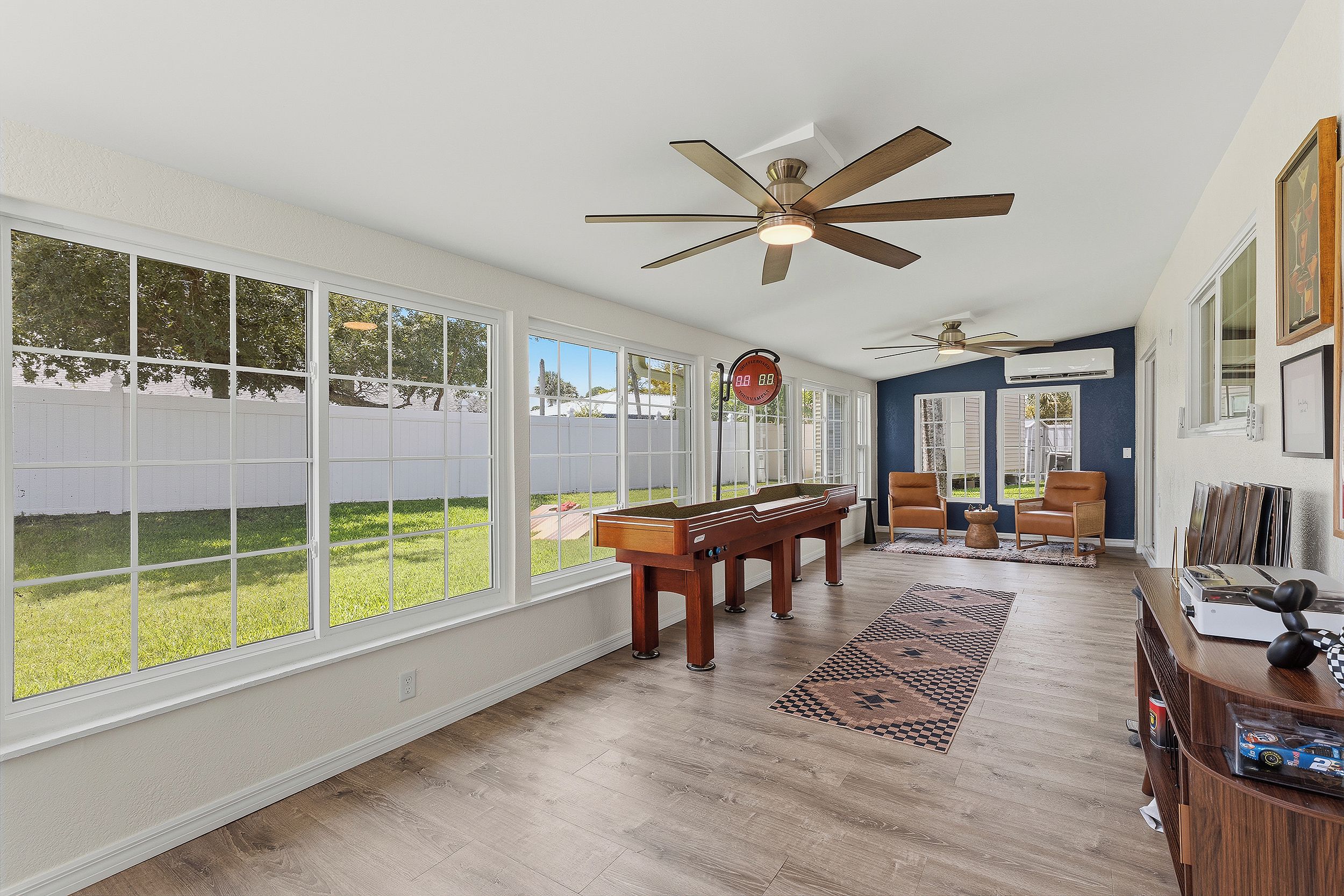 A spacious room with a pool table, ceiling fans, and a view of a backyard.