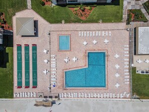 Ein Luftbild eines Hotels mit Schwimmbad, Liegestühlen und Tennisplatz.