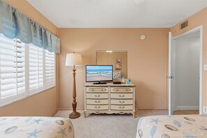 Ein Schlafzimmer mit Bett, Kommode, Fernseher und einer Tür.