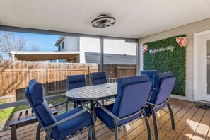 An outdoor patio with a round table and six blue chairs, a wooden fence, and a green wall with a 'Positive Vibes Only' sign. - New Lux Large Modern House 15min to ATX & Airport (Austin)