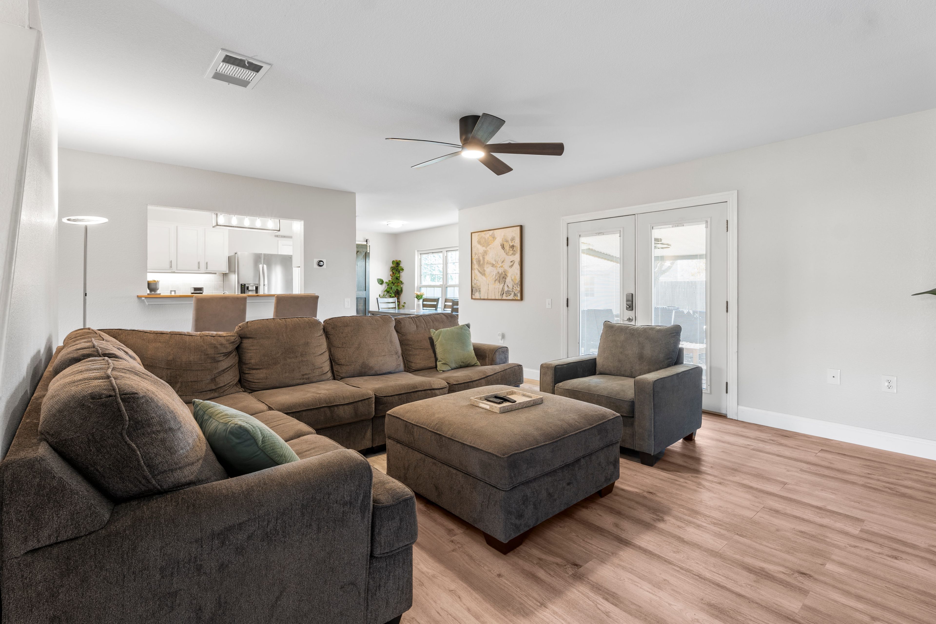 A modern living room with a sectional sofa, a grey armchair, and a wooden floor.